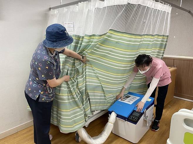 지난달 16일 서울시립 남부노인전문요양원에서 지내는 85살 와상환자의 침대 옆에 배설 돌봄로봇이 설치돼 있다. 이정효 간호과장(왼쪽)과 정후남 요양보호사가 로봇을 어떻게 사용하는지 설명하고 있다. 황보연 기자