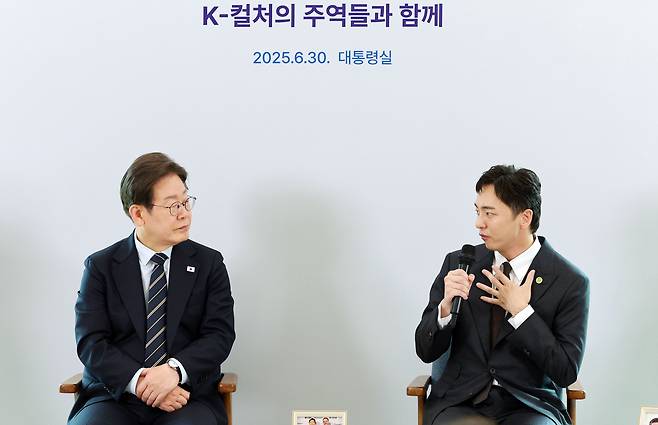이재명 대통령이 30일 서울 용산 대통령실 파인그라스에서 열린 문화예술계 수상자 간담회에서 토니상 6관왕을 석권한 뮤지컬 ‘어쩌면 해피엔딩’ 박천휴 작가의 발언을 듣고 있다. [연합]