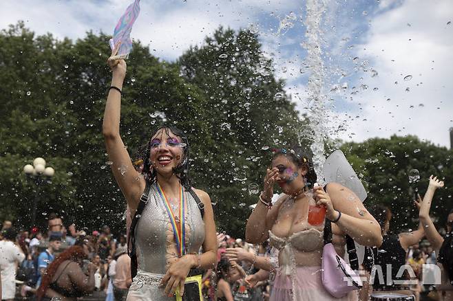 [뉴욕=AP/뉴시스] 29일(현지 시간) 미 뉴욕주 뉴욕에서 열린 프라이드 퍼레이드를 마친 여성들이 워싱턴 스퀘어 파크 분수대에서 물놀이를 하고 있다. 매년 6월은 '세계 성소수자 프라이드의 달'로 세계 곳곳에서 기념행사가 열린다. 2025.06.30.