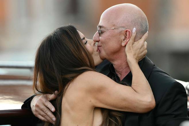 28일(현지시각) 이탈리아 베네치아에서 열린 결혼 축하 행사 사흘째 날, 아마존 창업자 제프 베이조스와 배우자 로런 산체스 베이조스가 아만 호텔을 떠나며 입맞춤을 나누고 있다. /AFP=연합뉴스