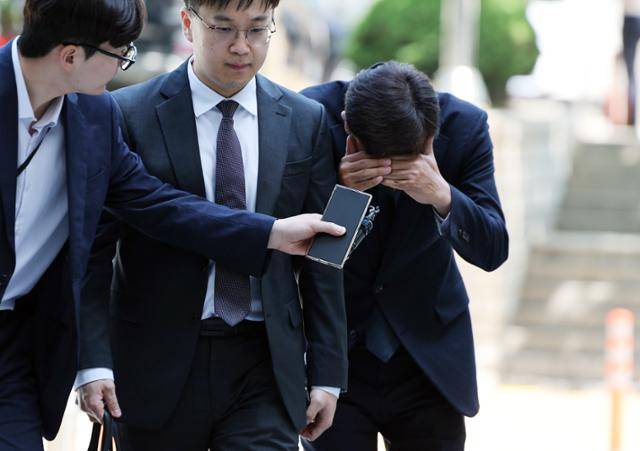 수백억대 부당 대출 혐의를 받는 IBK기업은행 전 직원 김모씨가 지난달 11일 서울 서초구 서울중앙지법에서 열린 구속 전 피의자 심문(영장실질심사)에 출석하며 양손으로 얼굴을 감싸고 있다. 뉴스1