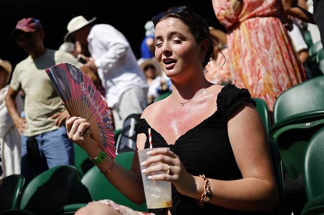 지난다 ㄹ30일(현지시간) 영국 런던에서 열린 메이저 테니스 대회 윔블던에서 한 관객이 더위를 호소하며 부채를 흔들고 있다. [EPA]