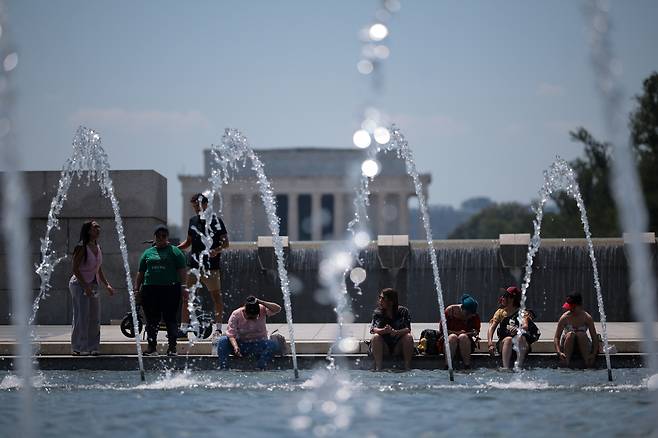 지난  24일(현지시간) 미국 워싱턴 DC의 내셔널몰에 있는 제2차 세계대전 기념 수영장에 방문객들이 발을 담그고 있다. [게티이미지]