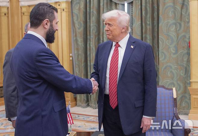 [리야드(사우디아라비아)=AP/뉴시스] 도널드 트럼프 미국 대통령은 30일(현지 시간) 시리아에 대한 제재를 공식 해제하는 행정명령에 서명했다. 사진은 트럼프 대통령(오른쪽)이 지난 5월 14일 사우디아라비아 리야드에서 아메드 알샤라 시리아 임시 대통령과 악수하는 모습. 2025.07.01.