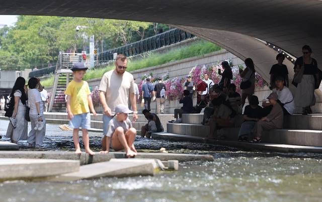 서울 청계천을 찾은 시민과 관광객들이 모전교 아래 그늘에서 햇볕을 피하고 있다. 연합뉴스