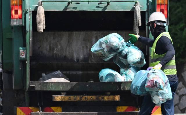2일 창원과학체험관 앞에서 한 가로청소 노동자가 그늘에서 휴식을 취하고 있다./성승건 기자/ 창원의 한 주택가에서 작업용 두건으로 얼굴을 감싼 청소노동자가 쓰레기를 수거차량에 싣고 있다./김승권 기자/