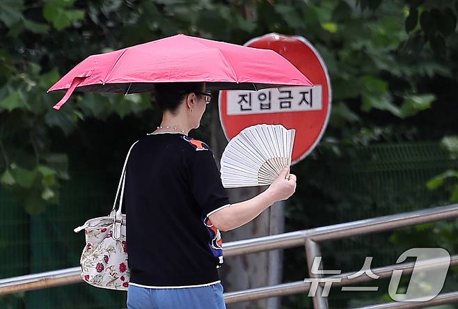 무더위가 이어진 1일 서울 여의도에서 양산을 든 시민이 부채질을 하며 이동하고 있다. 2025.7.1/뉴스1 ⓒ News1 박지혜 기자