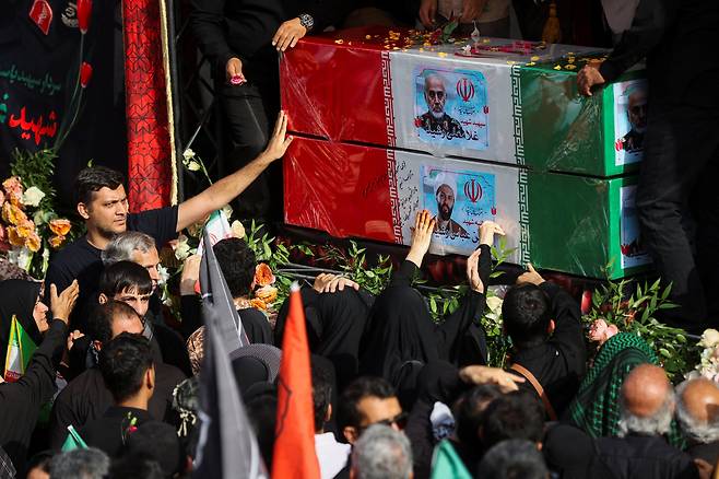 /로이터 연합뉴스지난달 28일 이란 테헤란에서 이스라엘과 이란의 교전 기간에 사망한 군 고위 관계자와 핵 과학자들을 비롯한 사망자에 대한 추모식이 거행됐다. 검은 옷을 입고 참석한 대중이 사망한 이들의 사진이 부착된 이란 국기로 덮은 관을 손 뻗어 어루만지고 있다.