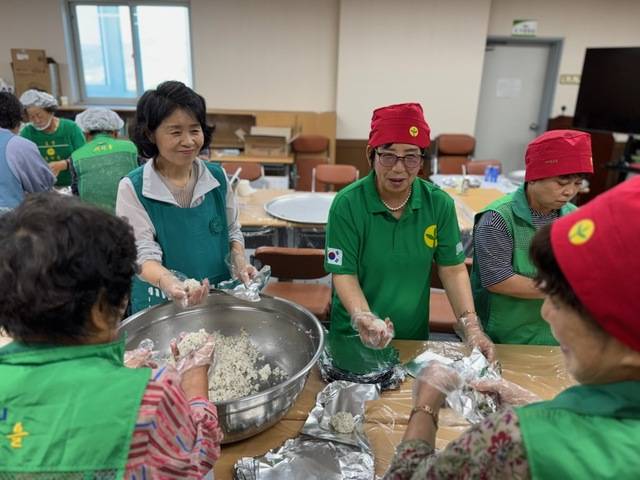 군위새마을부녀회원들이 이른 아침부터 군부대 이전 기념 싱싱코리아 축제장을 찾은 주민들에게 나눠줄 사랑이 담긴 주먹밥을 싸느라 분주한 모습이다. 이정희 여사도 손을 보탰다. 새마을회 제공.