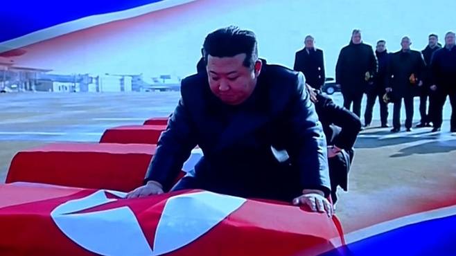 김정은 북한 국무위원장이 러시아로 파병한 북한군 전사자의 유해가 담긴 관을 어루만지고 있다. 이 장면은 지난달 29일 평양에서 올가 류비모바 러시아 문화부 장관이 참석한 가운데 열린 예술인 공연 중 무대 배경화면으로 공개됐다. /조선중앙TV 연합뉴스