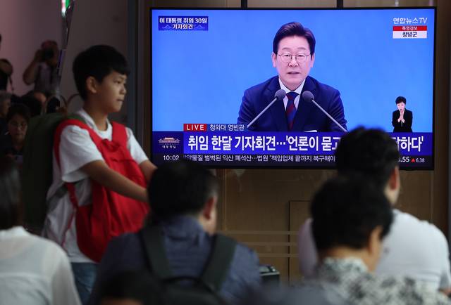 이재명 대통령의 취임 30일 첫 기자회견이 진행된 3일 중구 서울역에서 시민들이 방송을 지켜보고 있다.<연합뉴스 사진>