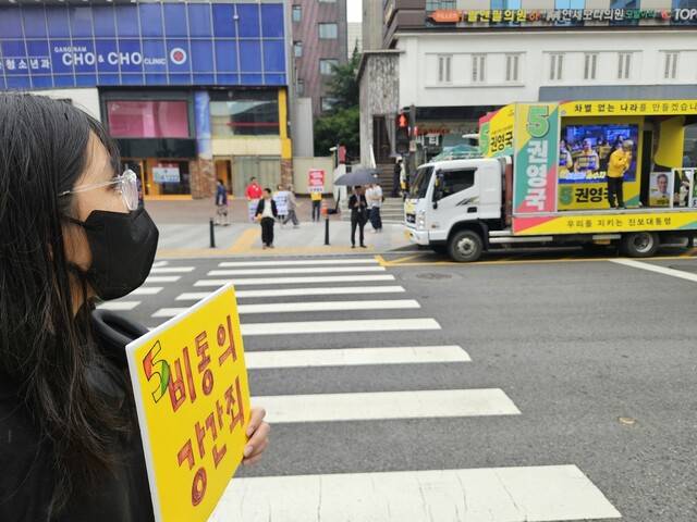 이지연(25·가명)씨가 2025년 6월2일 권영국 당시 민주노동당 대선 후보의 서울 강남역 유세 현장에서 ‘비동의강간죄\'라고 적힌 손팻말을 들고 서 있다. 류석우 기자