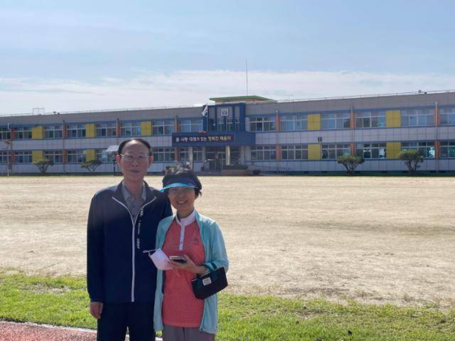 2년 전, 이춘희씨가 남편과 함께 충남 논산에 있는 남편의 모교 앞에서 활짝 웃고있다. 이씨 제공