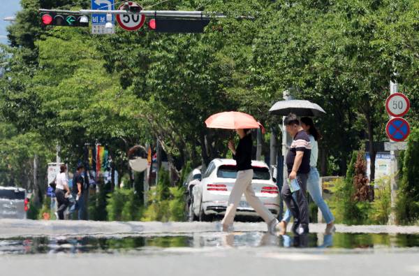 전국 대부분 지역에 폭염 특보가 발효된 3일 광주 서구 치평동에서 시민들이 강렬한 햇빛에 달구어져 아지랑이가 피어오르는 도로를 걷고 있다. 연합뉴스