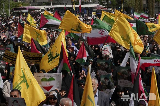 [테헤란=AP/뉴시스] 지난 4월 11일(현지 시간) 이란 수도 테헤란에서 시위대가 팔레스타인과 레바논 헤즈볼라 깃발을 흔들며 연대를 표하고 있다. 2025.07.03.