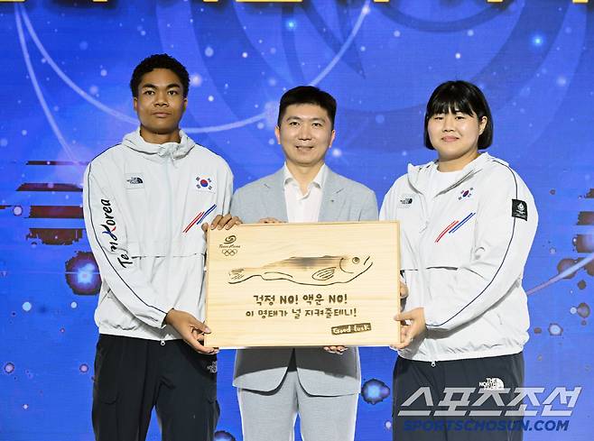 유승민 대한체육회장이 선수단의 액운을 막고 행운을 기원하는 마음을 담은 '액막이 명태' 기념품을 선수대표 나마디 조엘 진(육상), 김하윤(유도) 에게 전달하고 있다.  사진제공=대한체육회