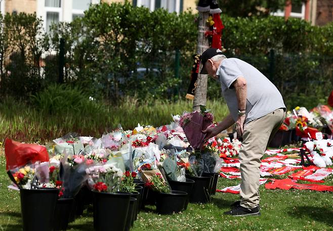 영국의 한 축구팬이 리버풀 홈구장 안필드 스타디움 앞에 디오주 조타의 죽음을 추모하는 꽃다발을 놓고 있다.   [로이터]