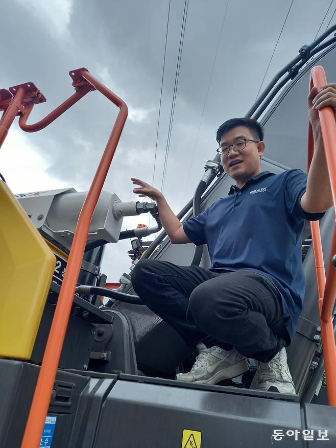 정태랑 레디로버스트머신 대표이사가 자사 중장비 에너지 회수 장치가 설치된 30t급 굴착기에 올라서 작동 원리를 설명하고 있다. 정 대표 뒤쪽으로 보이는 굴착기의 붐(Boom)이 아래로 움직일 때 버려지던 유압을 축압기에 저장했다가 다시 사용한다. 장치는 간편하게 탈부착이 가능하다. 김해=허진석 기자 jameshur@donga.com