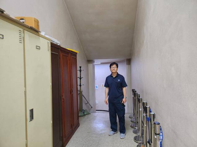 1일 서울고등법원에서 만난 전기 공무직 노동자 서호양(60)씨가 지하 사무실로 내려가기 전 카메라를 바라보고 있다. 지하로 내려가는 통로 양옆에는 오래된 캐비과 옷 걸이 등이 놓여 있었다. 송주용 기자