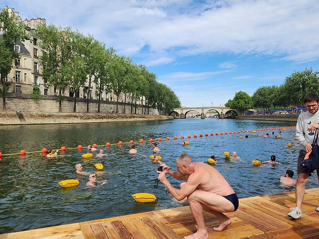 친구 사진찍어주는 남성. (파리=연합뉴스) 송진원 특파원 = 프랑스 파리 센강 마리 수로에 5일(현지시간) 문을 연 수영장에 시민들의 발길이 이어졌다. 시민들은 저마다 인증샷을 찍으며 추억을 남겼다. 2025.07.05. san@yna.co.kr