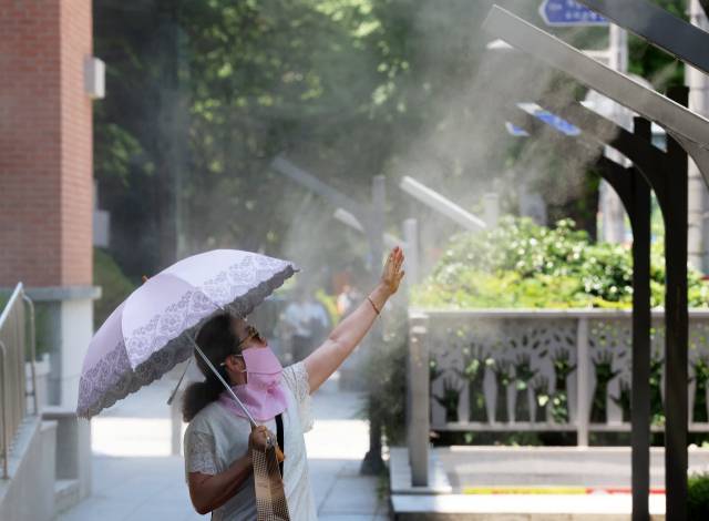 전국 대부분 지역에 폭염 특보가 발효된 3일 광주 동구 금남로에서 한 시민이 쿨링포그(안개형 냉각수)의 시원함을 만끽하고 있다. 연합뉴스