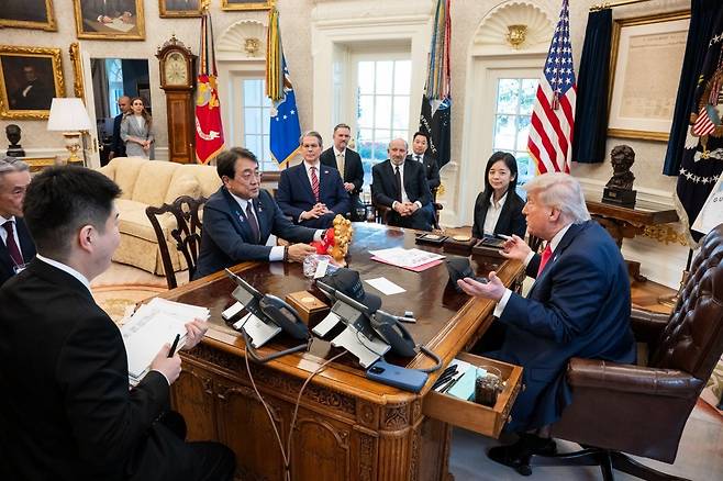 올 4월 트럼프 미국 대통령이 백악관 집무실에서 아카자와 료세이 일본 경제재생상과 만나 관세 협상을 하기 전 직접 서명한 모자를 건네고 있다. 책상 모퉁이에 휴대전화를 올려뒀다. 사진 출처 백악관