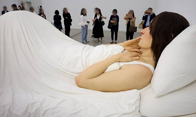 지난 5월20일 서울 종로구 국립현대미술관 서울관을 찾은 관람객이 론 뮤익의 작품 ‘침대에서’를 감상하고 있다. 연합뉴스