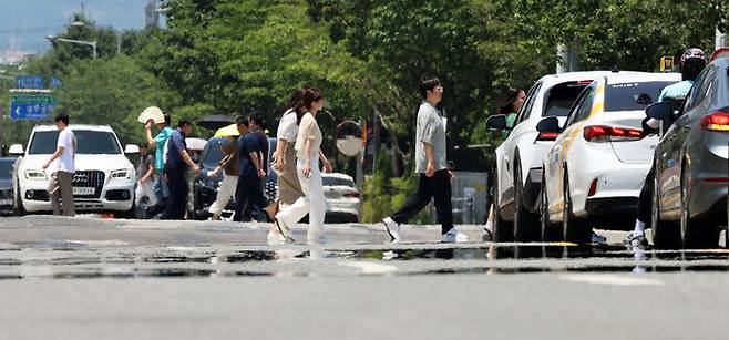 전국 대부분 지역에 폭염특보가 발효된 지난 3일 광주 서구 치평동에서 시민들이 강렬한 햇빛에 달구어져 아지랑이가 피어오르는 도로를 걷고 있다. 연합뉴스