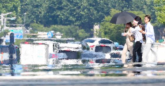 Citizens walk across a heated road in Daegu on June 27, the day that the city saw its first heatwave advisory of 2025. [YONHAP]