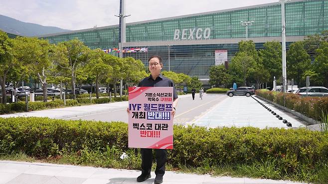 탁지일 소장이 지난 4일 부산 벡스코 정문 앞에서 월드캠프 개최를 반대하는 내용의 팻말을 들고 1인 시위를 벌이고 있다. 부산성시화운동본부 이단상담소 제공