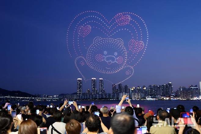 [부산=뉴시스] 하경민 기자 = 폭염특보와 열대야 현상으로 인해 밤낮으로 푹푹 찌는 더위가 이어진 5일 밤 부산 수영구 광안리해수욕장을 찾은 시민과 관광객들이 드론쇼를 구경하고 있다. 2025.07.06. yulnetphoto@newsis.com