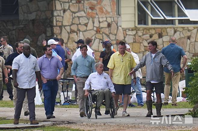 [AP/뉴시스] 휠체어를 탄 텍사스주의 그렉 애버트 주지사가 홍수 발생 하루 뒤인 5일 과달루프강 제방의 미스틱 캠프를 둘러보고 있다