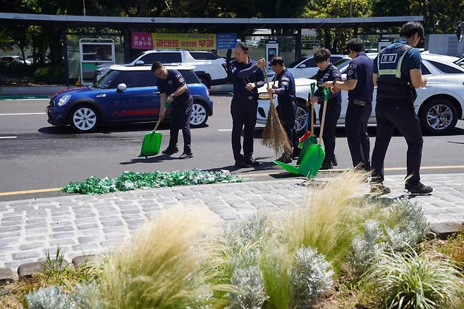 7일 신제주로터리 도로 위로 쏟아진 소주병과 상자를 치우는 도청 청원경찰들.