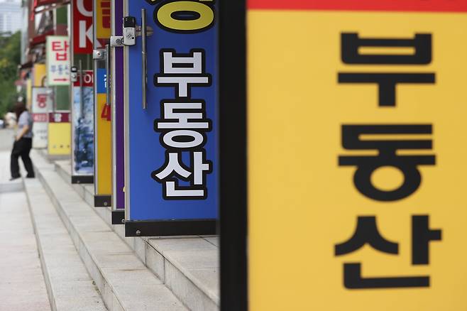 서울의 한 부동산 중개업소 앞에 시민이 오가고 있다./연합뉴스
