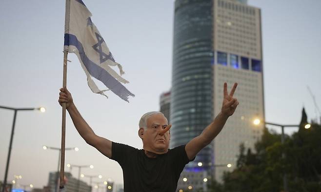 5일(현지시각) 이스라엘 텔아비브에서 인질 석방을 요구하는 시위에 참여한 이가 베냐민 네타냐후 총리 가면을 쓰고 있다. 텔아비브/AP 연합뉴스