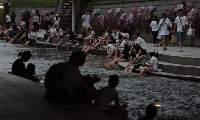 People escape the heat at Cheonggyecheon in Jongno-gu, central Seoul, Sunday evening as the city experienced a tropical night phenomenon for the seventh consecutive day. (Yonhap)