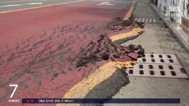 울산 북구 한 도로의 아스팔트가 밀려서 하수구 일부를 덮은 모습. SBS 보도 화면 캡처