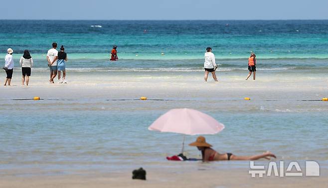 [제주=뉴시스] 우장호 기자 = 폭염의 기세가 수그러들지 않는 6일 오후 제주시 한림읍 금능해수욕장을 찾은 피서객들이 시원한 바닷물에 발을 담그며 더위를 식히고 있다. 2025.07.06. woo1223@newsis.com