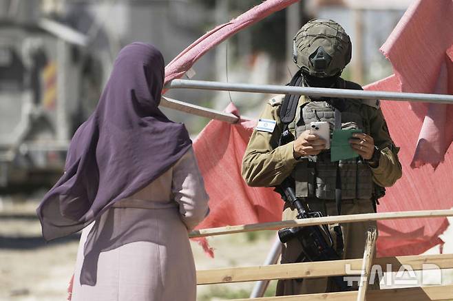 [툴카름=AP/뉴시스] 6일(현지 시간) 요르단강 서안지구 툴카름 난민촌에서 한 이스라엘군 병사가 팔레스타인 여성을 검문하고 있다. 이날 이스라엘 보안군의 주택 철거를 앞두고 주민들이 소지품을 챙겨 집을 떠나고 있었다. 2025.07.07.