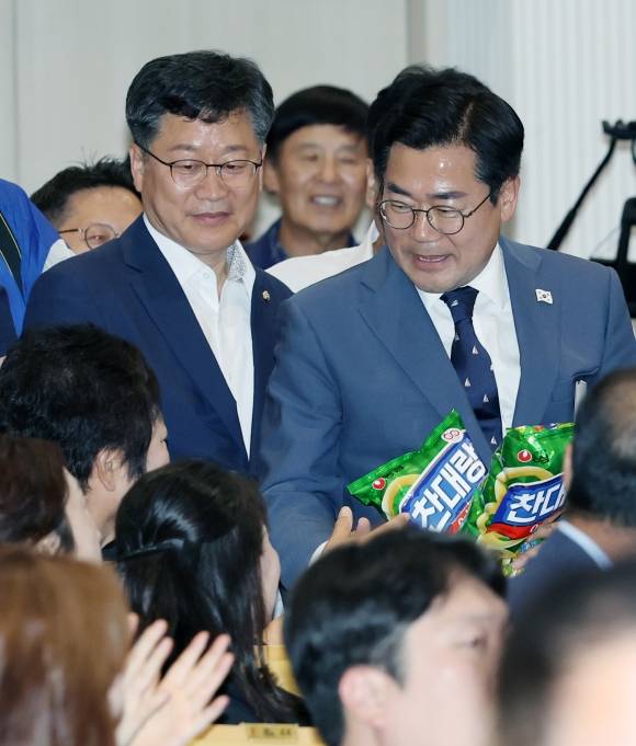불꽃 튀는 당심 경쟁 - 더불어민주당 당대표 선거에 출마한 박찬대(오른쪽) 의원이 지난 5일 전북 전주시 전주대 JJ아트홀에서 열린 토크콘서트에서 지지자에게 받은 과자를 들고 입장하고 있다. 전주 뉴스1