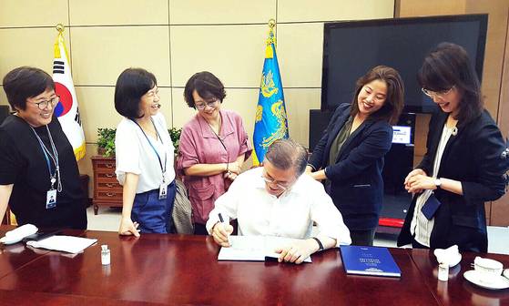 문재인 당시 대통령이 2019년 3월 22일 낮 청와대 여민1관에서 청와대비서실 여성 비서관들과 오찬을 함께 한 뒤 대통령 취임 1주년을 맞아 발간된 영문 연설집에 서명하고 있다. 사진 청와대