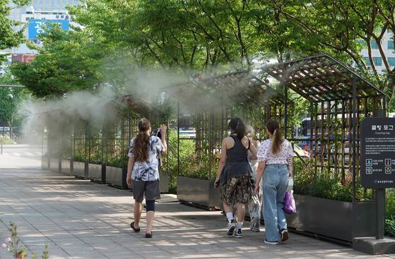 서울시청 앞에 설치된 쿨링포그 터널을 시민들이 지나고 있다. 쿨링포그는 물안개를 분사해 주변온도를 낮추는 장치다. 시는 올해 쿨링포그 설치 장소를 기존 147개소에서 21개소를 더해 168개소로 늘릴 계획이다. 사진 서울시
