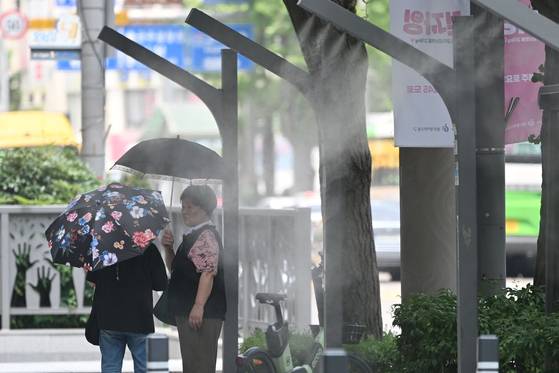 8일 오후 광주 동구 금남로에서 시민들이 양산을 쓴 채 쿨링포그가 뿜어내는 물안개를 맞고 있다. 뉴시스