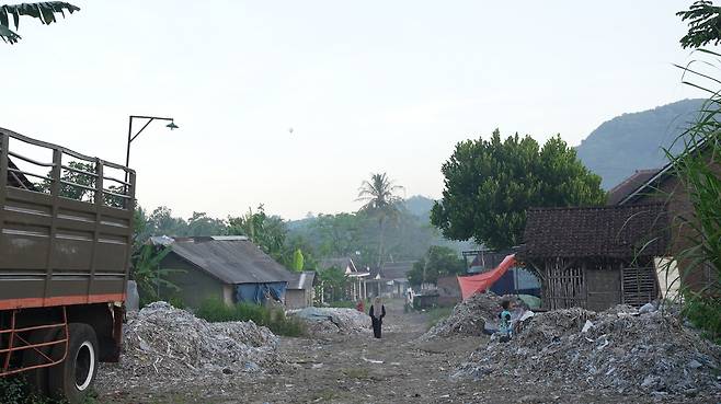 감핑안 마을이 연기 속에서 흐릿하게 보인다. 마을 하늘 위로 연이 떠 있다. 유혜민 감독 제공