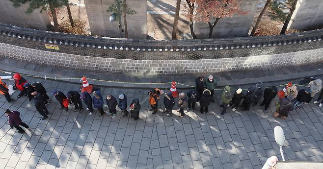 Elderly people wait in line for a free lunch at a soup kitchen in Jongno District, central Seoul, on Feb. 3. [YONHAP]