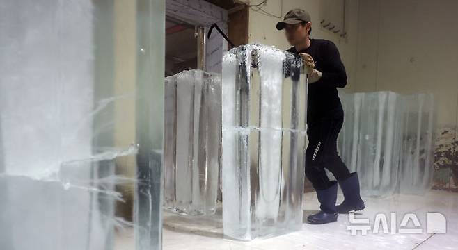 [인천=뉴시스] 전진환 기자 = 연일 폭염이 이어지는 8일 경기도 부천시 오정구의 한 얼음공장에서 직원이 생산한 얼음을 옮기고 있다.  2025.07.08. amin2@newsis.com