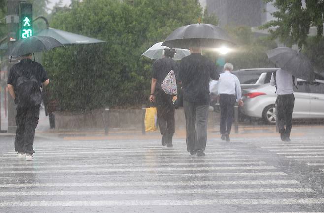 서울 서남권에 호우주의보가 발효된 8일 서울 영등포구 여의도 국회 인근에서 시민들이 우산을 쓰고횡단보도를 건너고 있다.연합뉴스