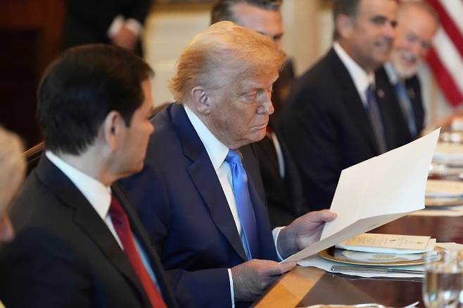 도널드 트럼프 미국 대통령이 7일(현지시간) 워싱턴DC 백악관 만찬 자리에서 베냐민 네타냐후 이스라엘 총리로부터 건네받은 노벨평화상 추천서를 살펴보고 있다. AP 연합뉴스