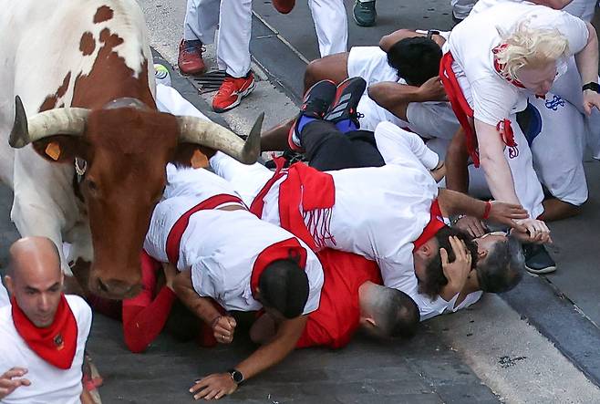 8일 스페인 팜플로나에서 열린 산페르민 축제에서 모조라고 불리는 주자들이 돌진하는 황소에 밀려 넘어져 바닥에 엎드려 있다. /EPA 연합뉴스