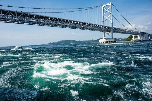 나루토해협의 소용돌이 뒤로 관조선과 나루토대교가 보인다.